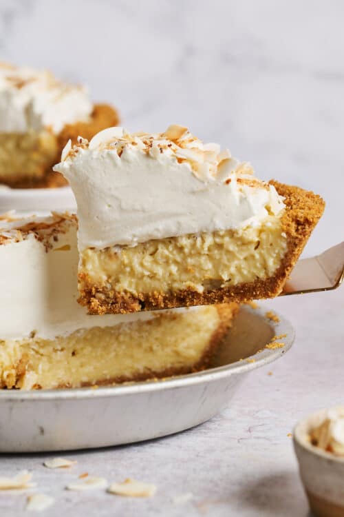 Slice of creamy coconut cream pie being lifted out of the pie plate.