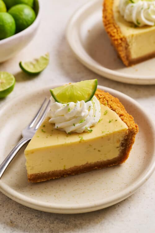 Slice of key lime pie on a plate with whipped cream on top.