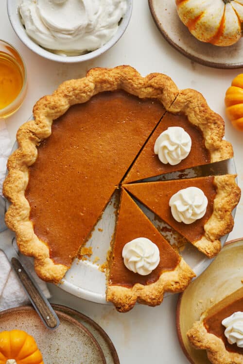 A bourbon pumpkin pie in the pie plate with whipped cream on top.